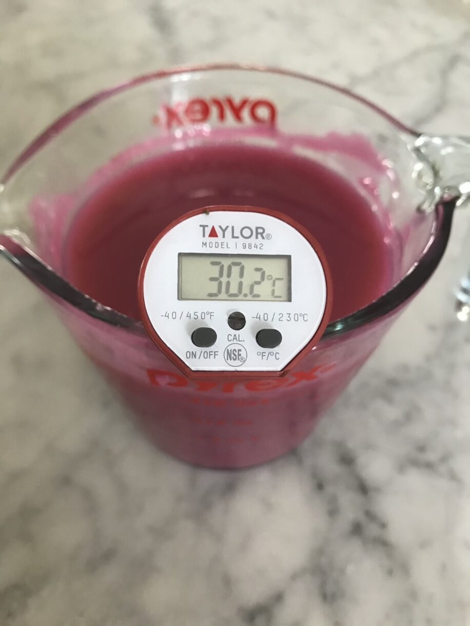 A thermometer in a glass jug, taking the temperature of entremet glaze