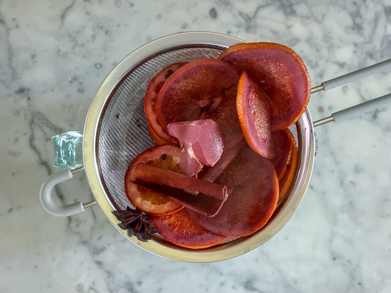 passing mulled wine through a strainer to remove spices and fruit