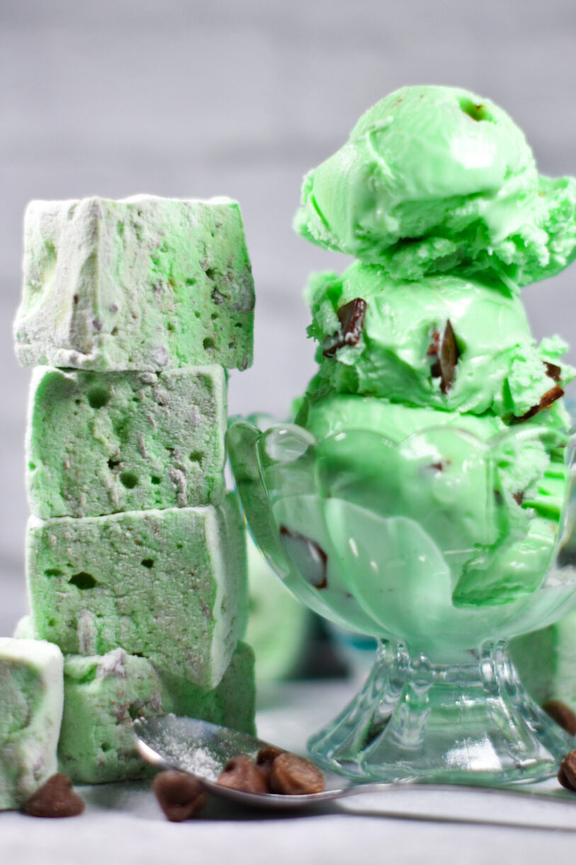 A stack of mint chocolate chip marshmallows next to a bowl of mint chocolate chip ice cream