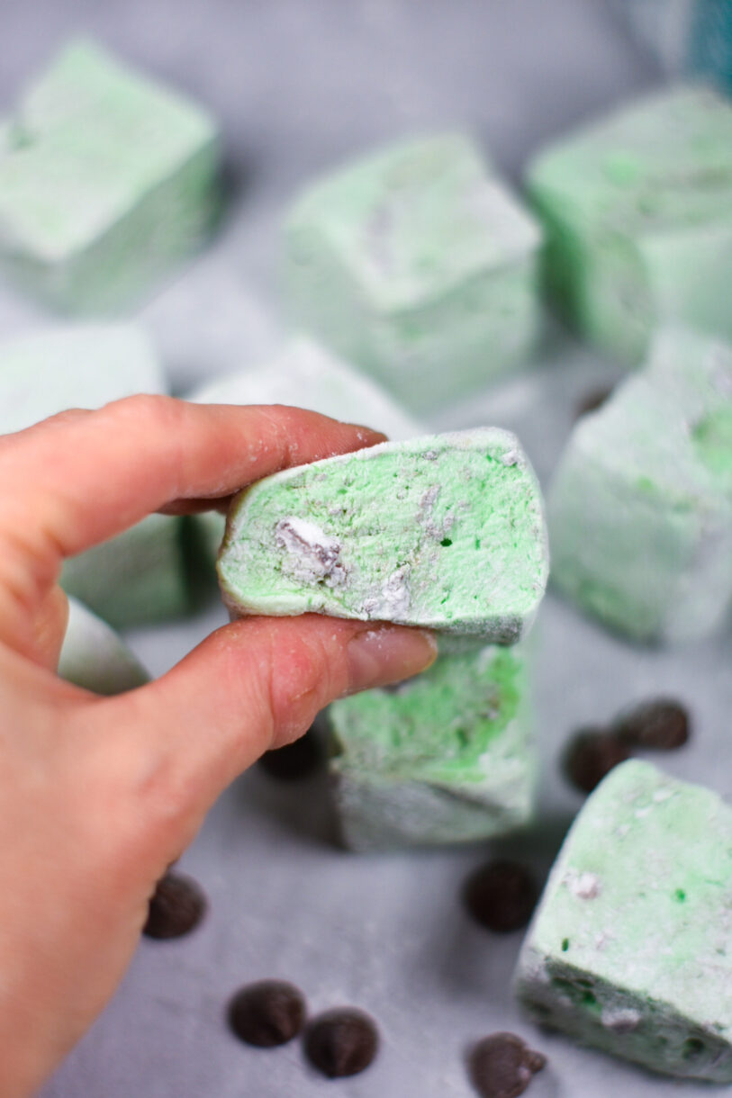 Hand squeezing a mint green marshmallow