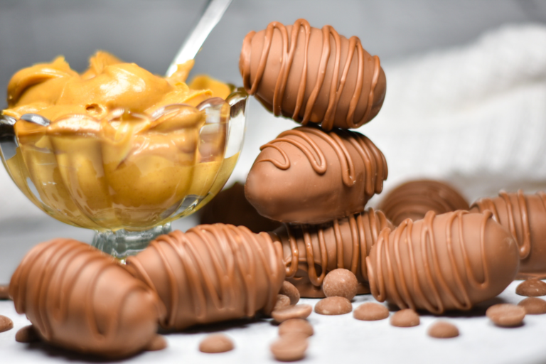 A stack of homemade peanut butter Easter eggs and a bowl of peanut butter on a white surface