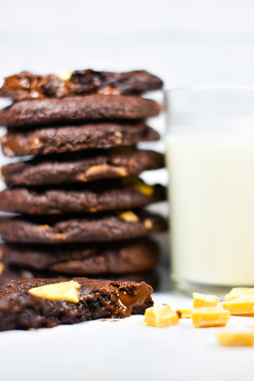Stack of chocolate cookies, a glass of milk, and broken pieces of passionfruit inspiration chocolate couverture