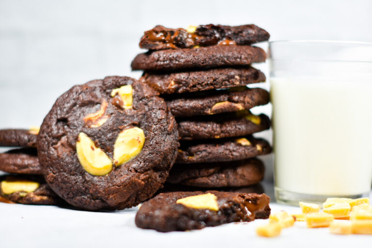 A stack of chocolate passionfruit cookies and a glass of milk