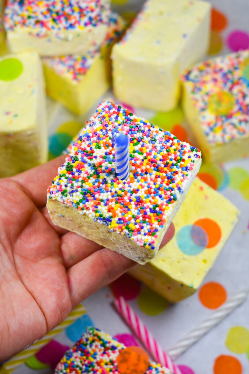 Hand holding a homemade marshmallow with a birthday candle on the top
