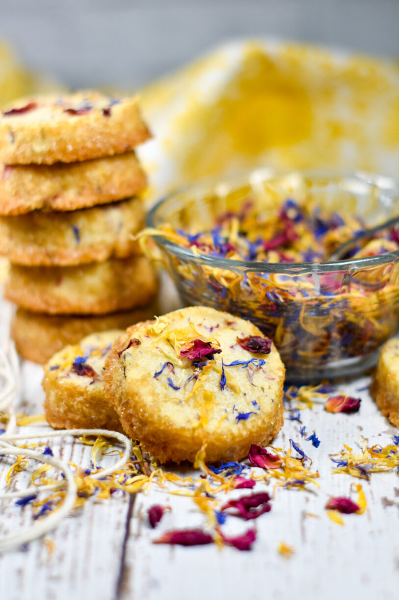 A stack of shortbread cookies and a bowl of edible dried flowers