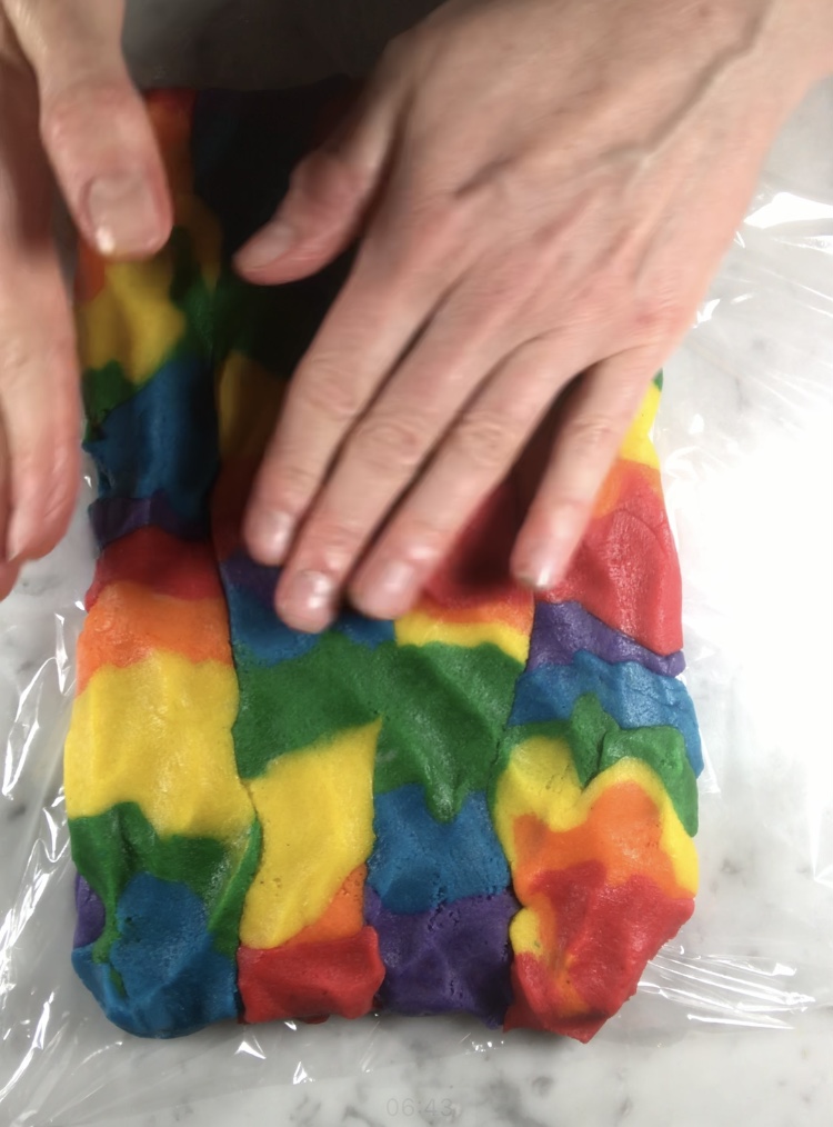 Hands shaping rainbow cookie dough