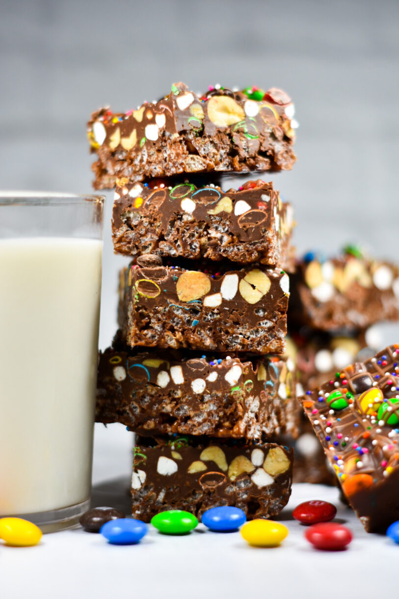 A stack of rainbow rocky road slices next to a glass of milk