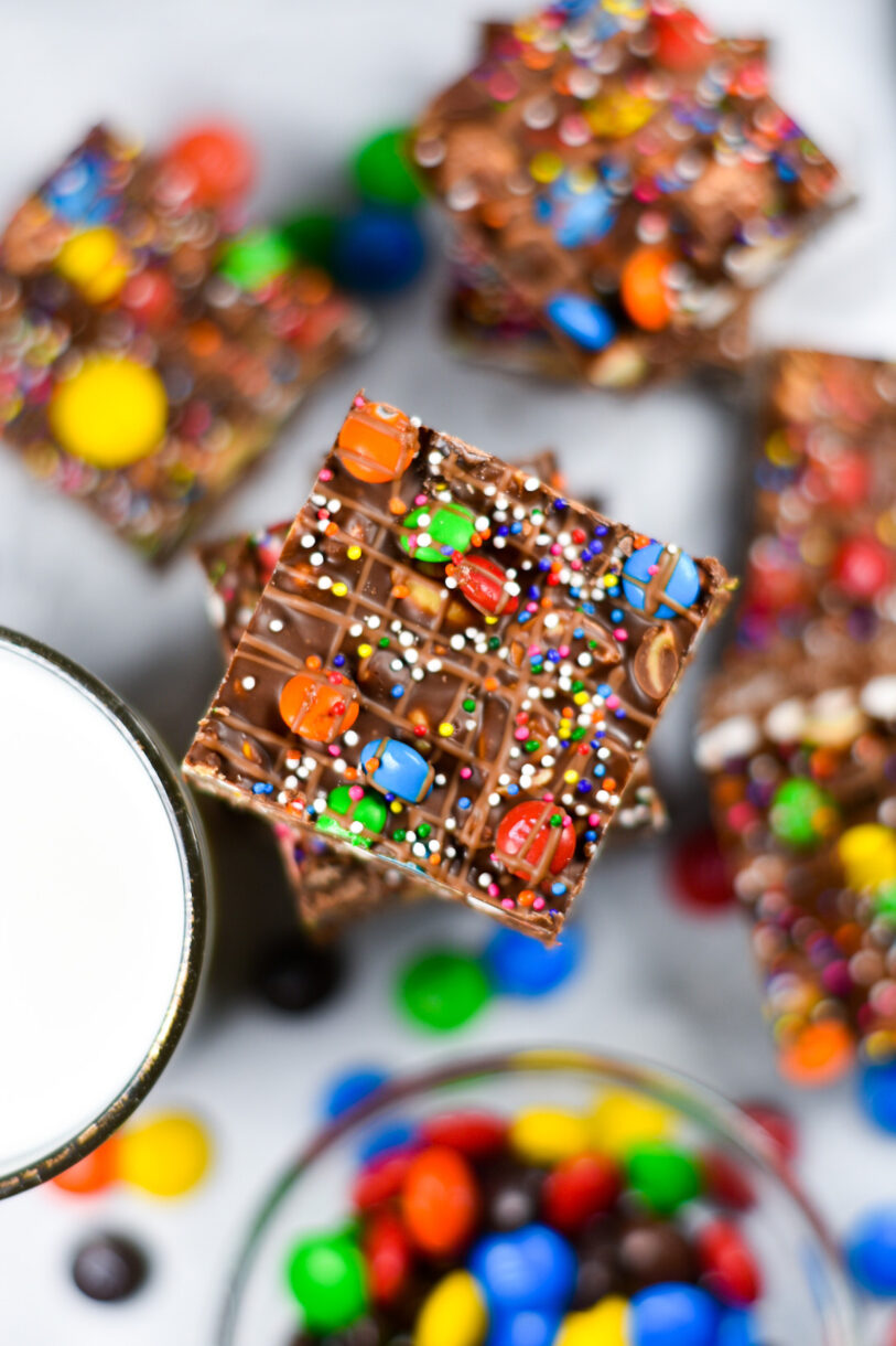 Looking down at a stack of rocky road decorated with M&Ms, rainbow sprinkles, and melted chocolate