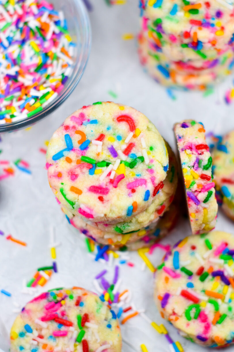 Overhead view of a stack of rainbow shortbread, next to a bowl of sprinkles