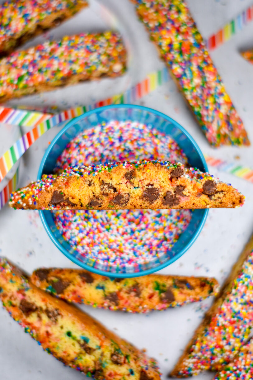 Chocolate Chip Rainbow Biscotti slices surrounding a bowl of sprinkles