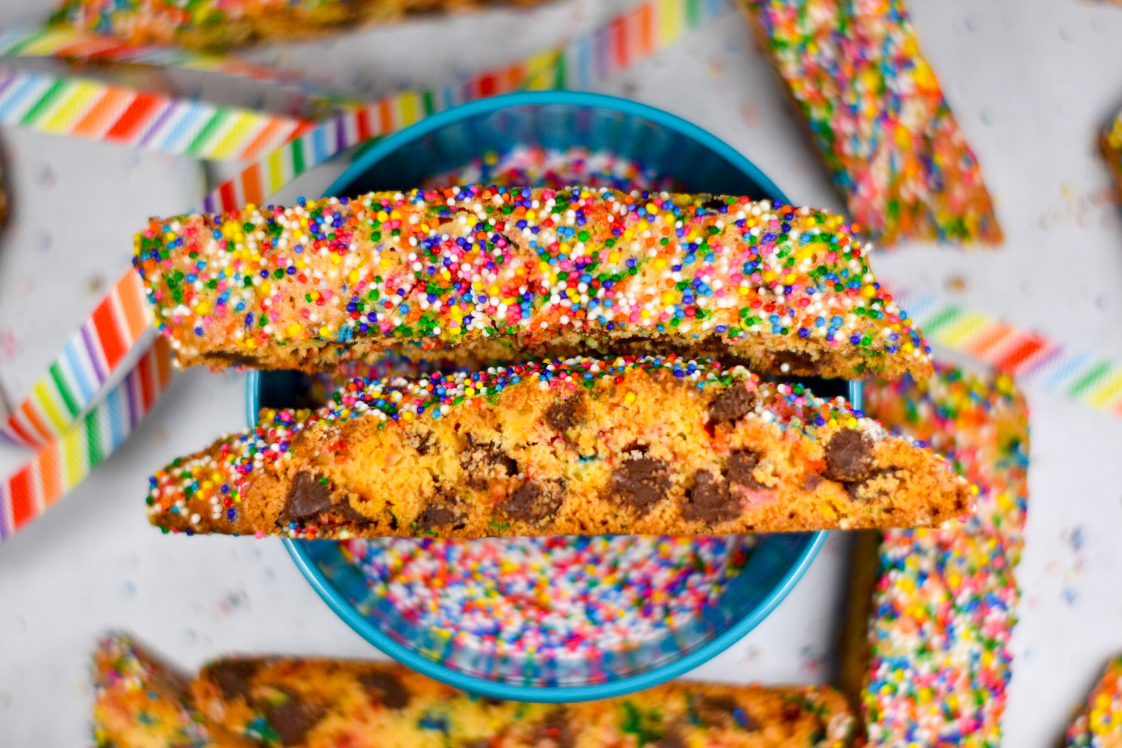 chocolate chip biscotti on top of a bowl of sprinkles