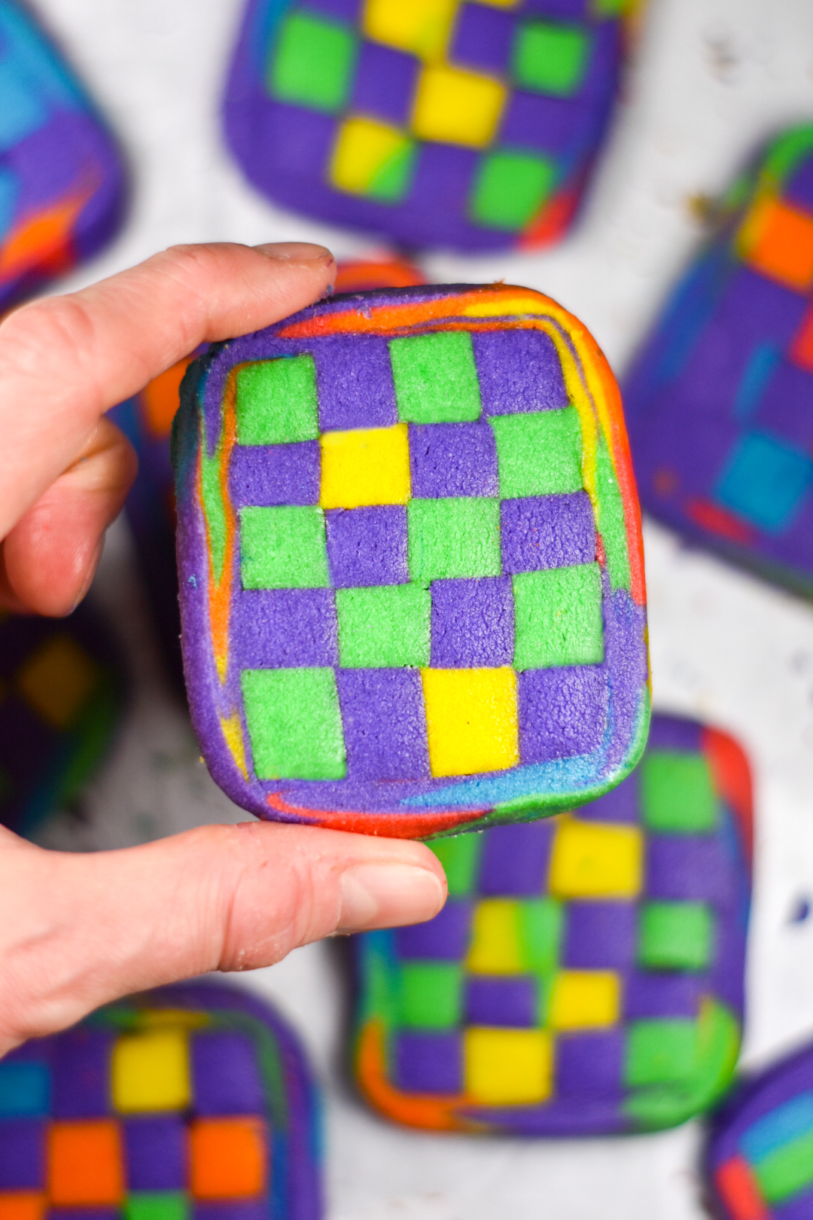 Hand holding a green, yellow and purple checkerboard cookie
