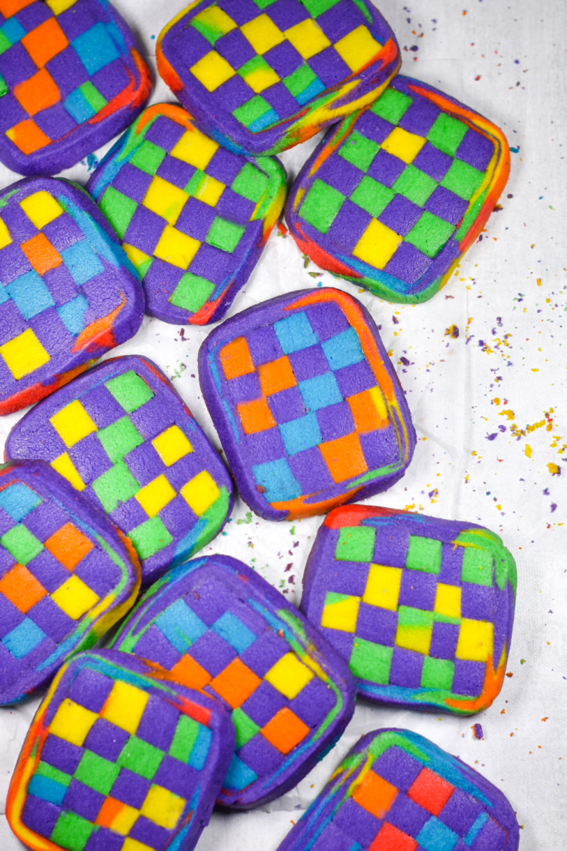 Geometric Rainbow Cookies aligned along the left side of a vertical photo, on a white background