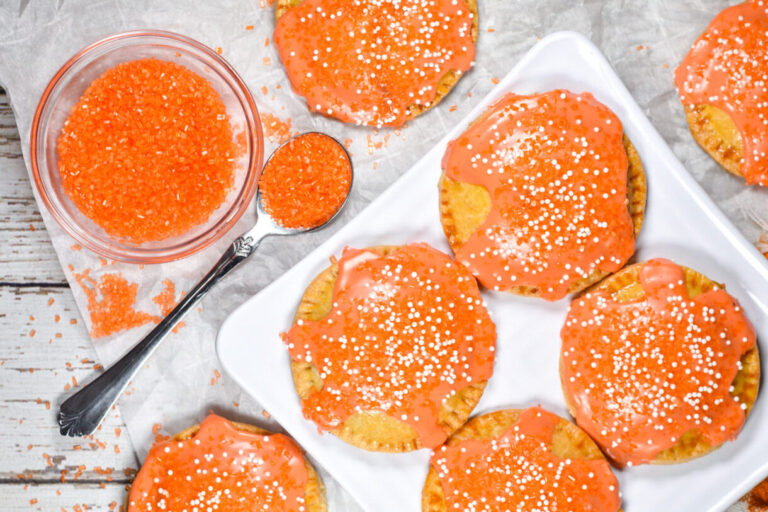 Peach and ginger hand pies on a square plate, accompanied by a spoon and bowl of sugar