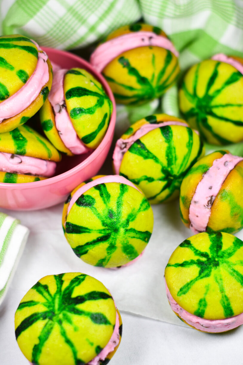 Watermelon whoopie pies on a white background, with a green tea towel