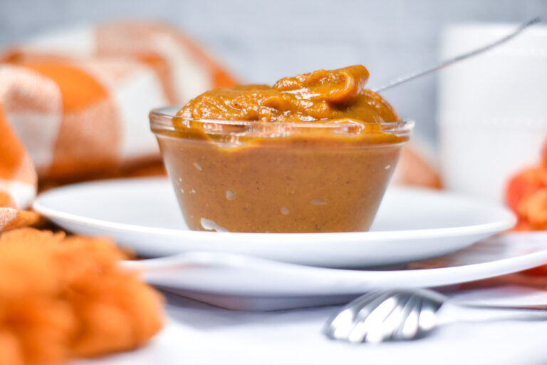 A glass bowl of spiced pumpkin spread sitting on a white plate