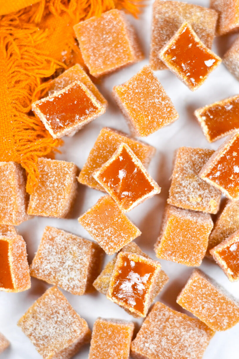 White surface with orange fringed tea towel and slices of carrot ginger candy
