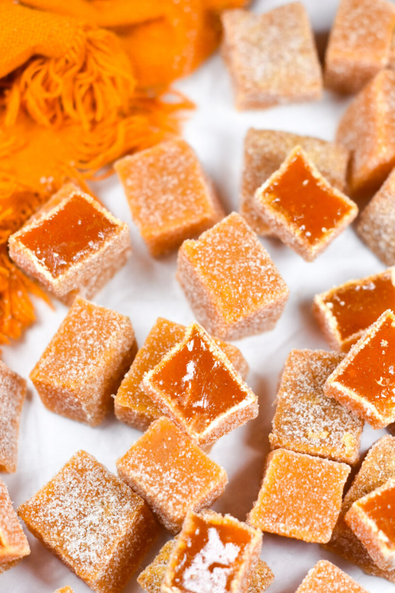 Slices of carrot ginger candy and an orange tea towel, on a white background