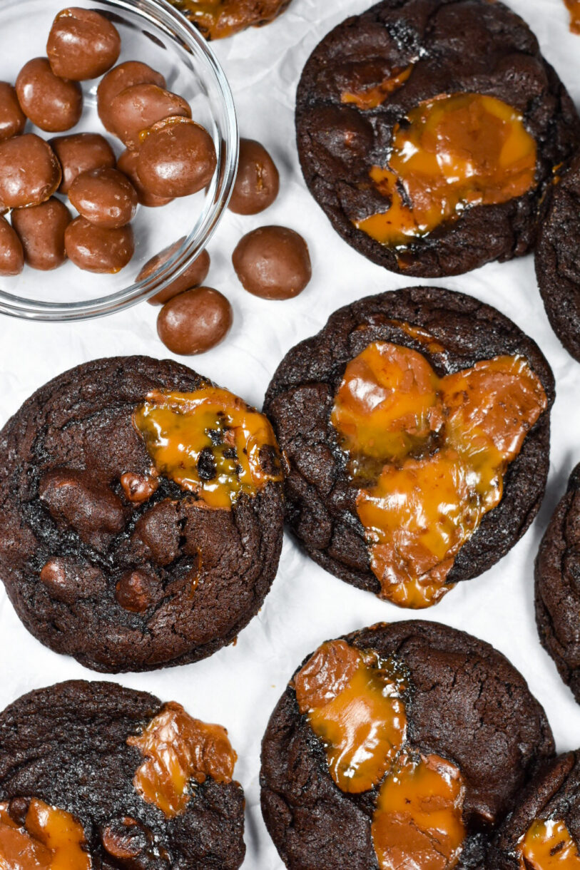 A bowl of Milk Dud candies surrounded by chocolate caramel cookies