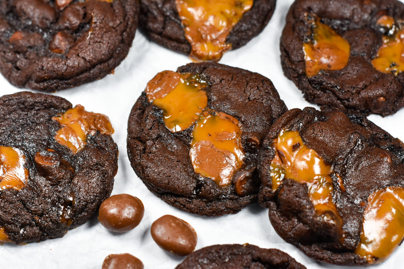 chocolate caramel cookies and Milk Duds on a white surface