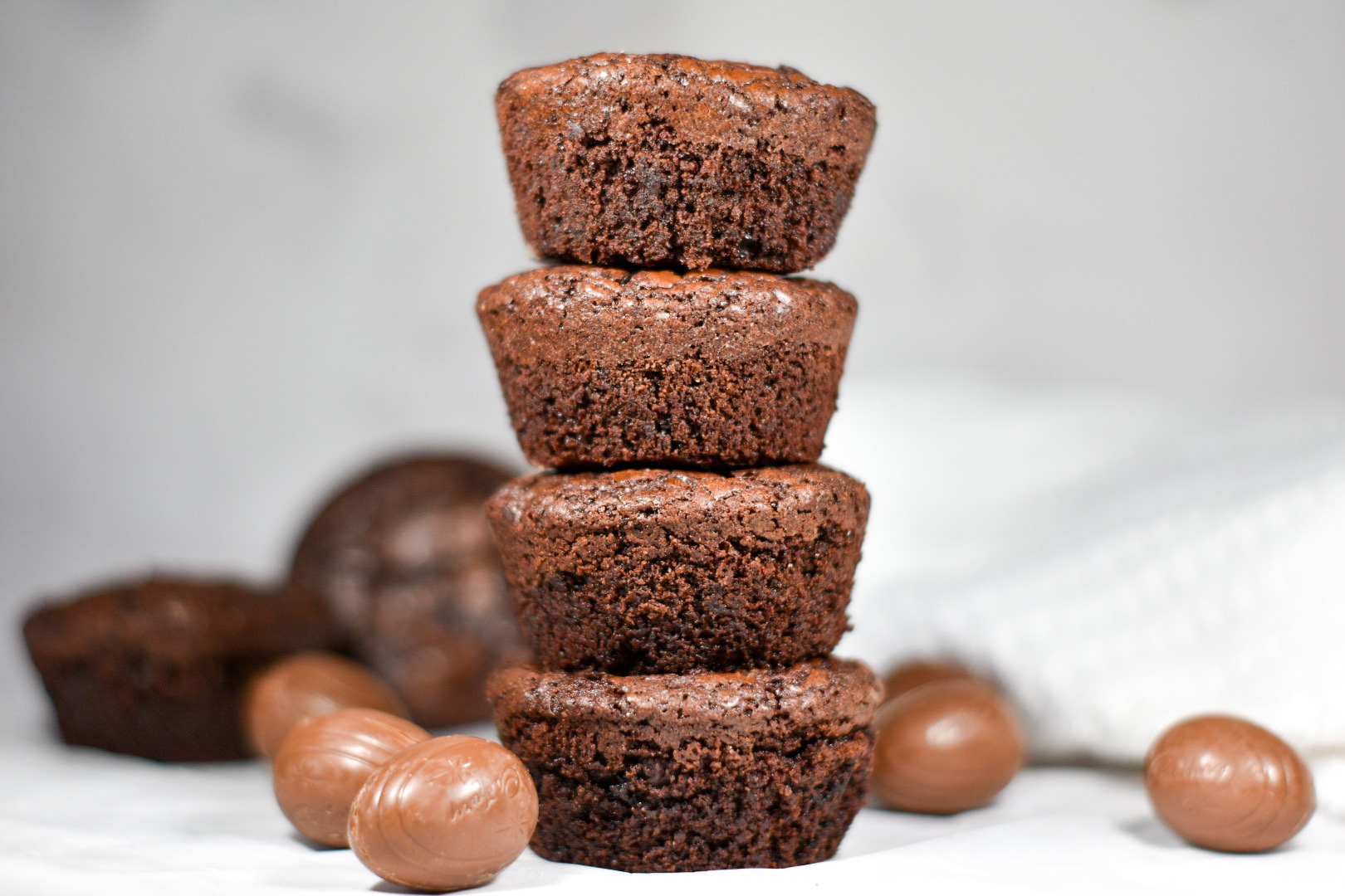 a stack of brownie cups surrounded by chocolate eggs