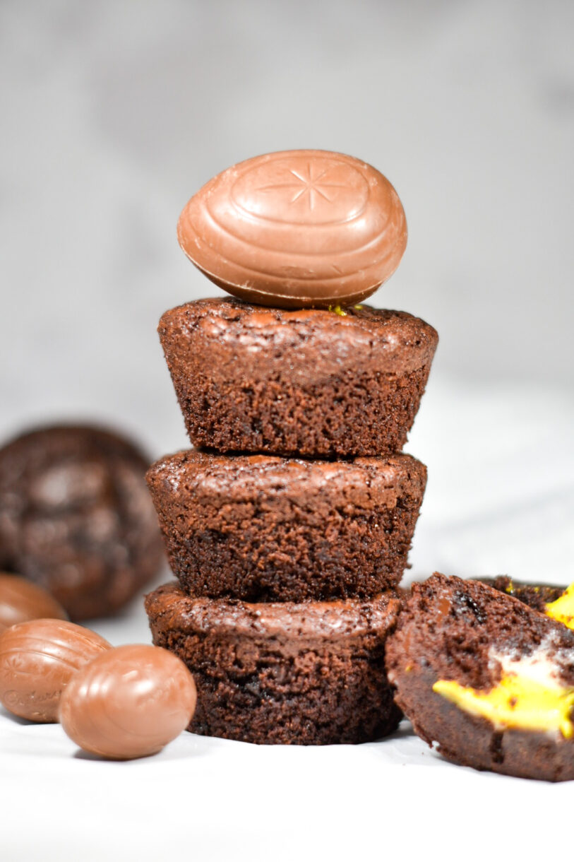 A stack of three creme egg brownie cups with a whole Cadbury egg balanced on top, made from an original brownie cup recipe
