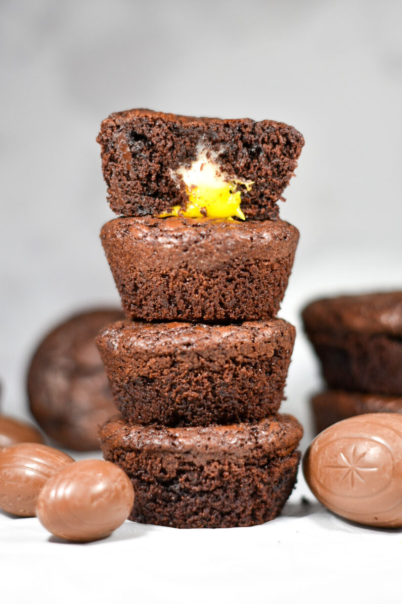 A stack of Cadbury egg brownie cups, with a half brownie on top and yellow and white cream visible
