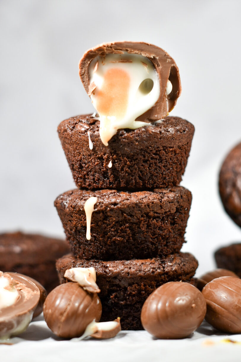 A stack of brownie cups with a sliced creme egg and cream dripping down the stack