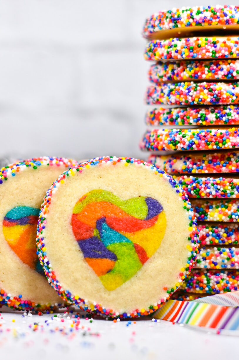Rainbow Slice and Bake Heart Cookies with a rainbow striped ribbon and stack of cookies in the background