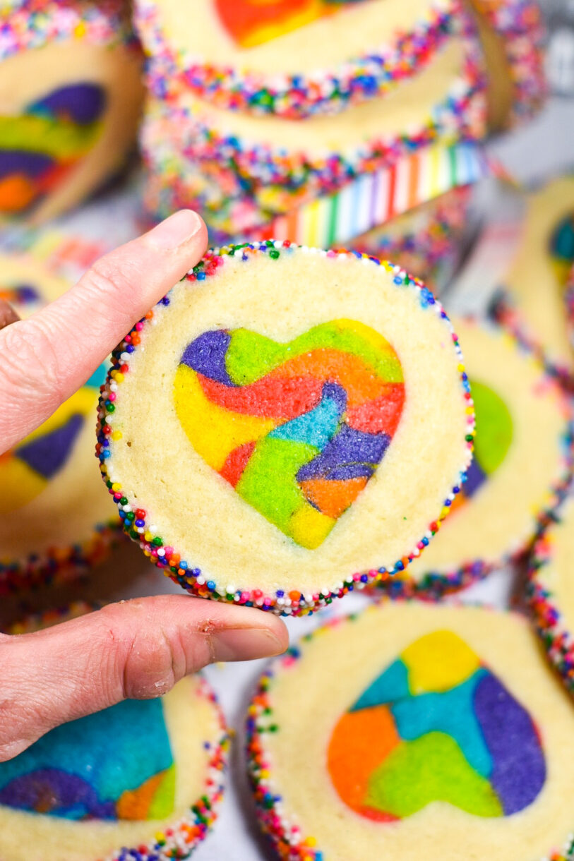 Hand holding a rainbow heart cookie
