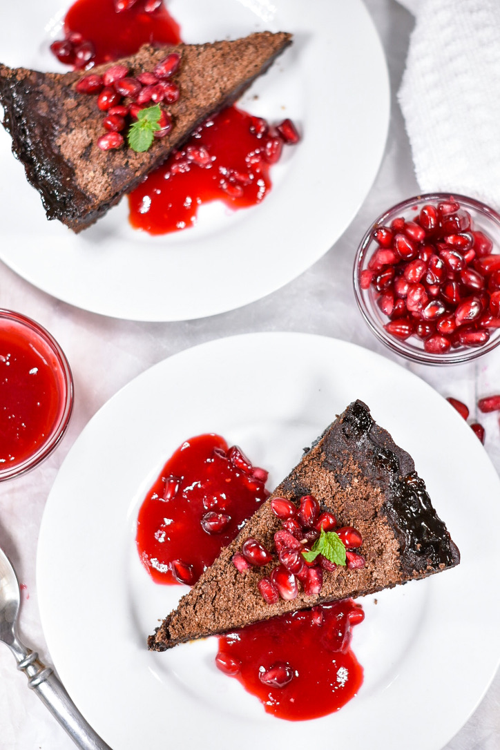 Two white plates with slices of chocolate shoo fly pie, pomegranate sauce, and pomegranate and mint garnish, photographed for Rebeccca's MSc Culinary Innovation Management studies