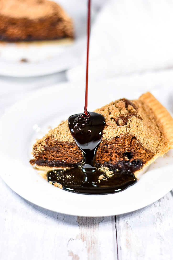 A photograph of a white plate with a slice of shoo fly pie, and molasses being drizzled over the top, prepared for MSc Culinary Innovation Management in London