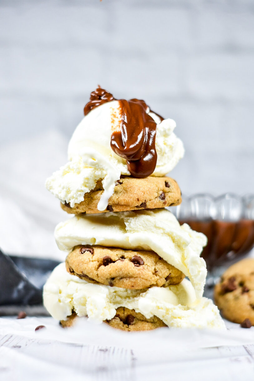 A stack of chocolate chip cookies and vanilla ice cream, with a drizzle of homemade hot fudge sauce on top