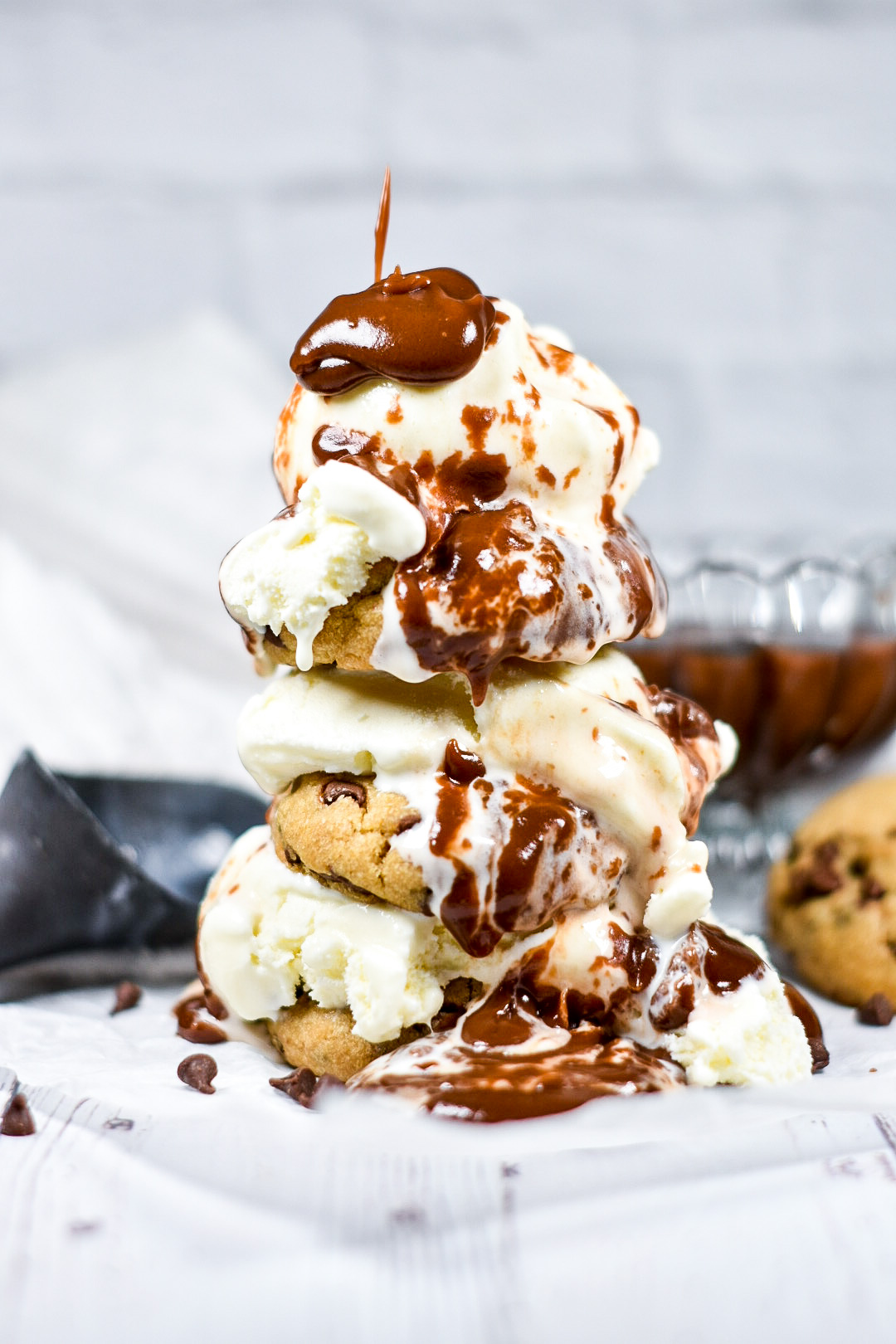 a stack of cookies and vanilla ice cream drizzled with fudge sauce
