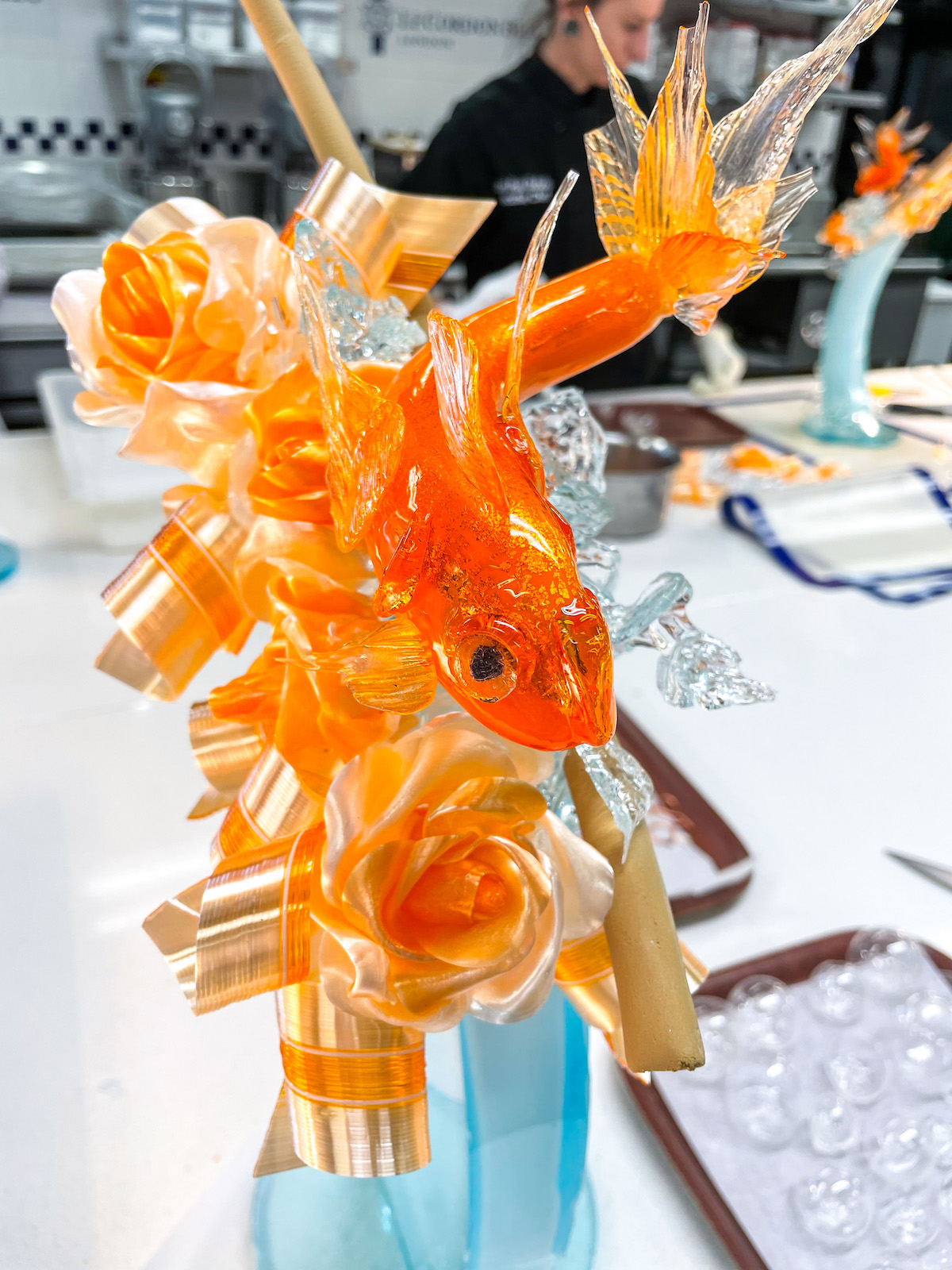 Fish themed sugar sculpture in a kitchen at Le Cordon Bleu London, with tools and sugar pieces surrounding it on the countertop