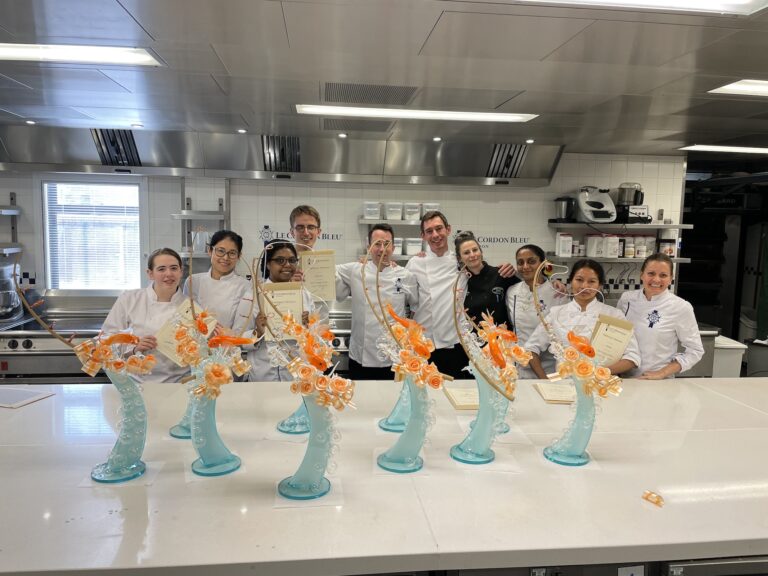 Student chefs at Le Cordon Bleu London displaying their certificates and finished work