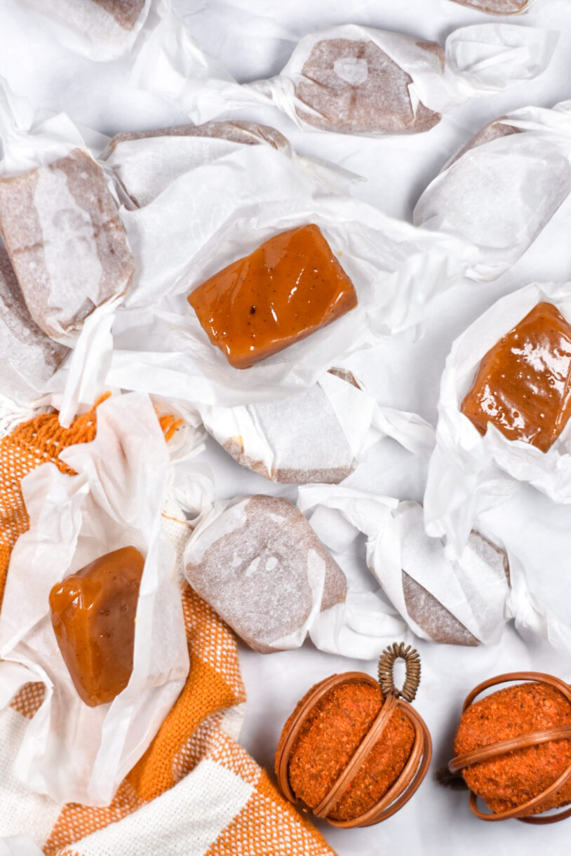 Wrapped and unwrapped caramels surrounded by decorative pumpkins