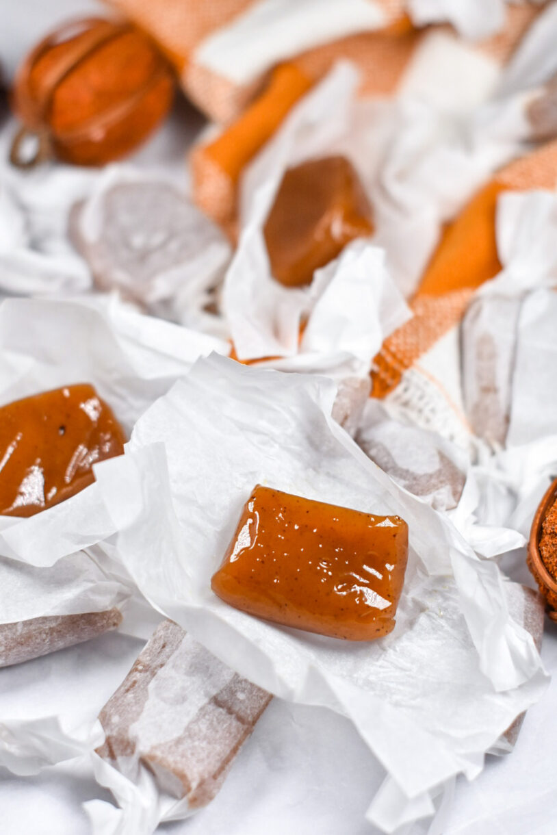 Wrapped and unwrapped caramels surrounded by decorative pumpkins