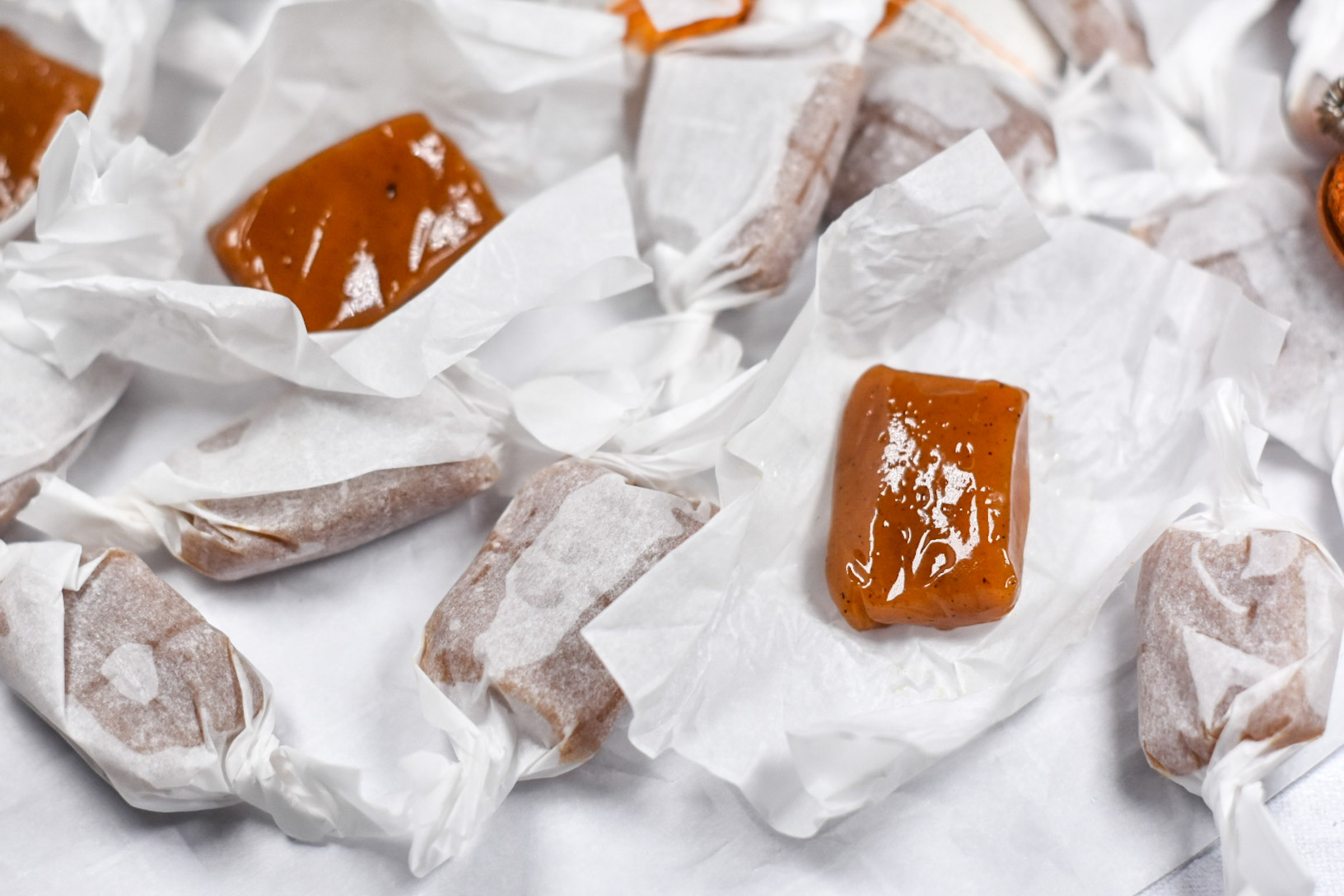 caramels and white parchment wrappers on a white surface