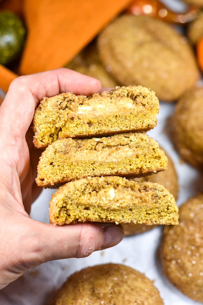 Hand holding a stack of three sliced pumpkin cream cheese cookies