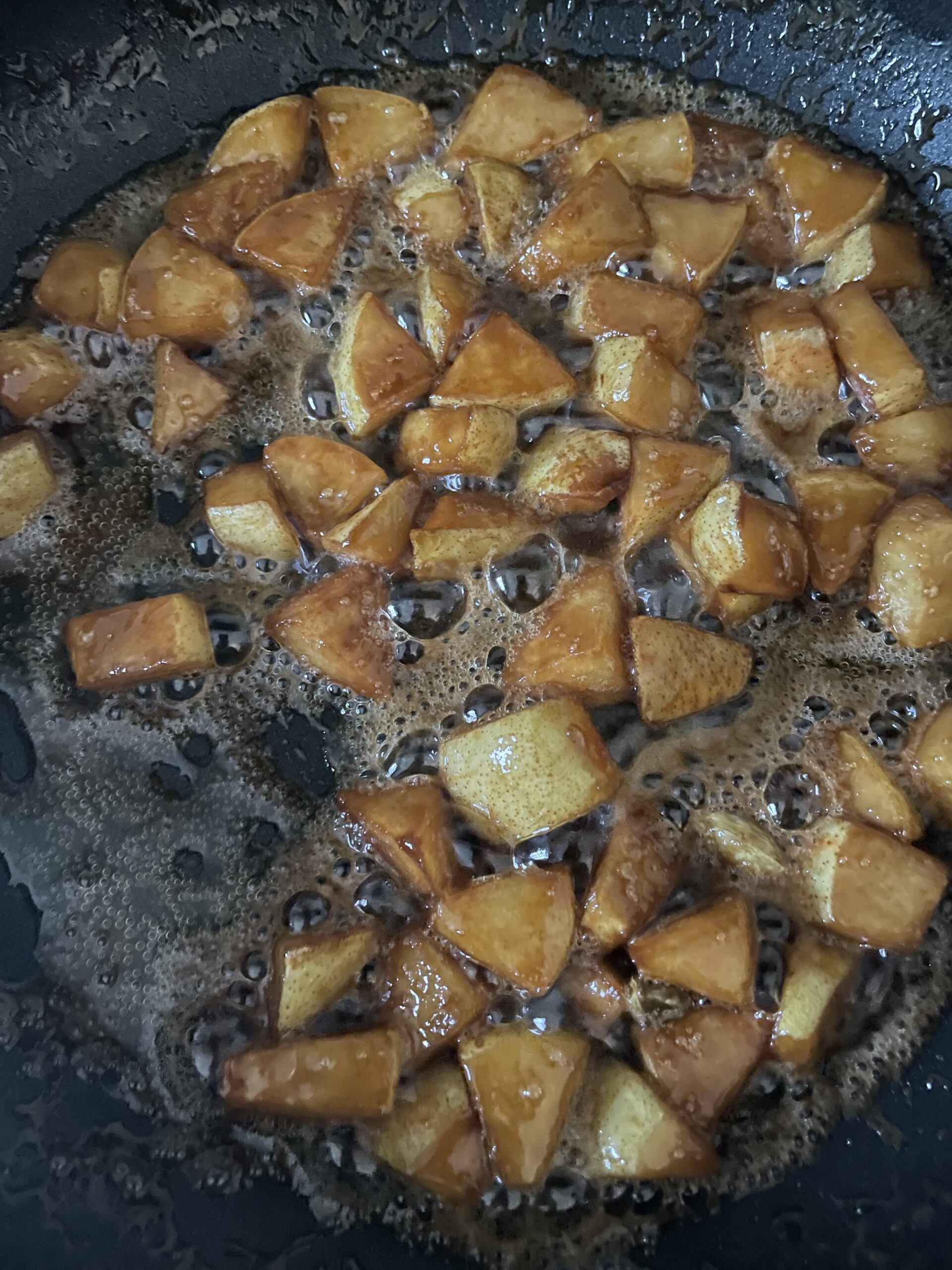 Chunks of pear caramelizing in a frying pan