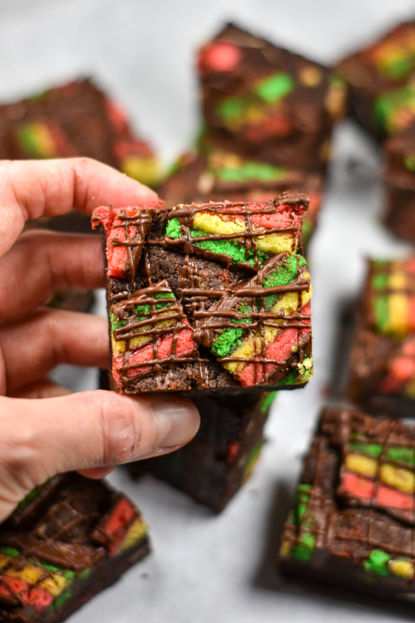A hand holding a brownie in the colors of the Italian flag, with drizzled chocolate on top