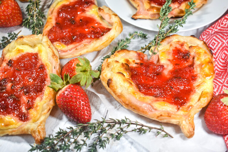 Puff pastry hearts with strawberry jam, on a white background with fresh berries and thyme sprigs