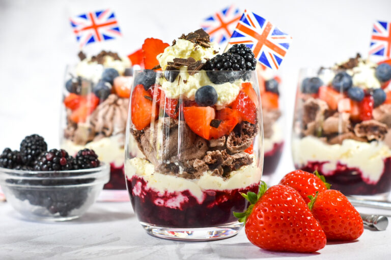 Eton Mess parfaits in clear glasses with fresh strawberries and blackberries nearby