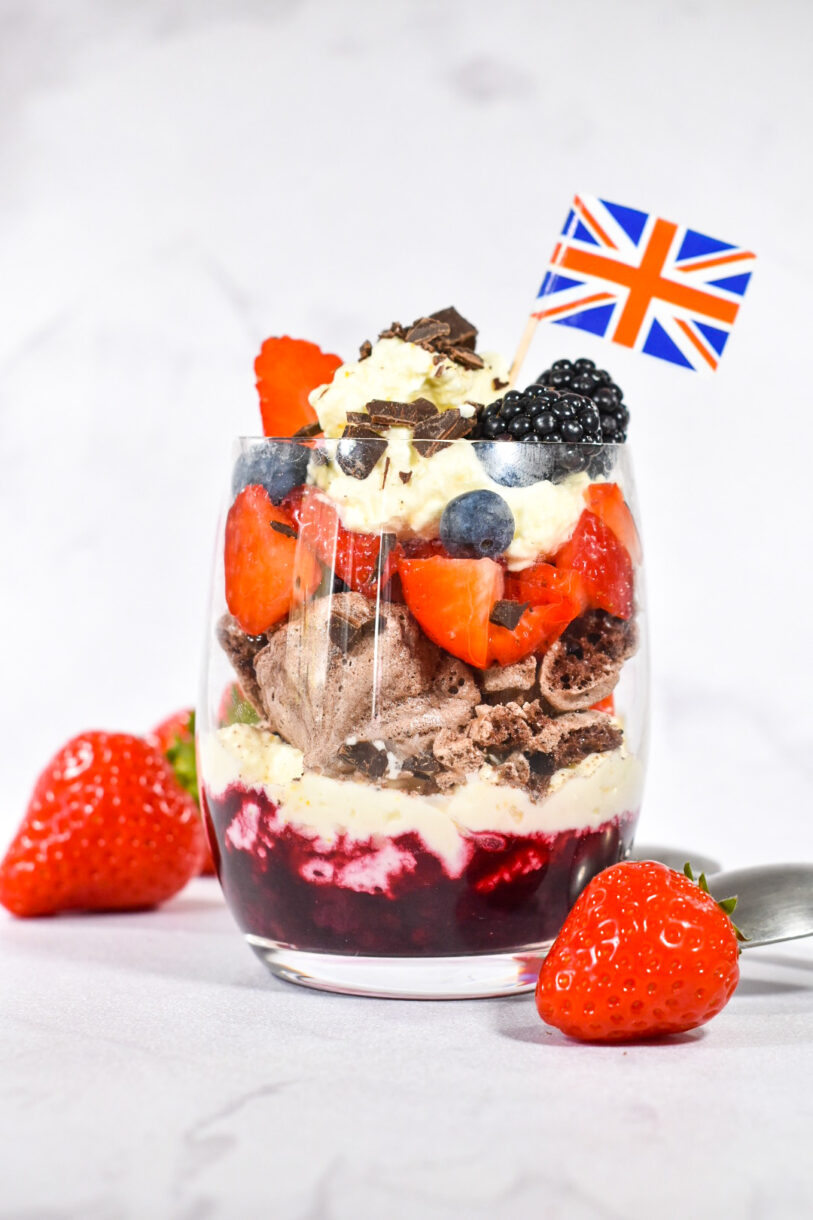 Triple Berry Eton Mess with Chocolate Meringue, photographed on a white background with two bright red strawberries