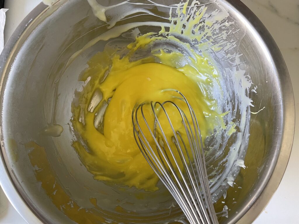 Bowl of yellow chocolate and whisk