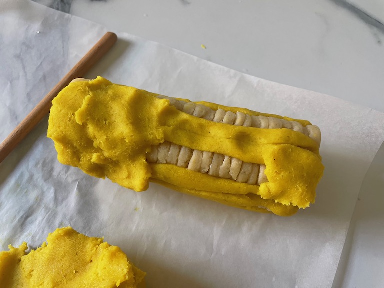 Packing yellow dough around daisy roll