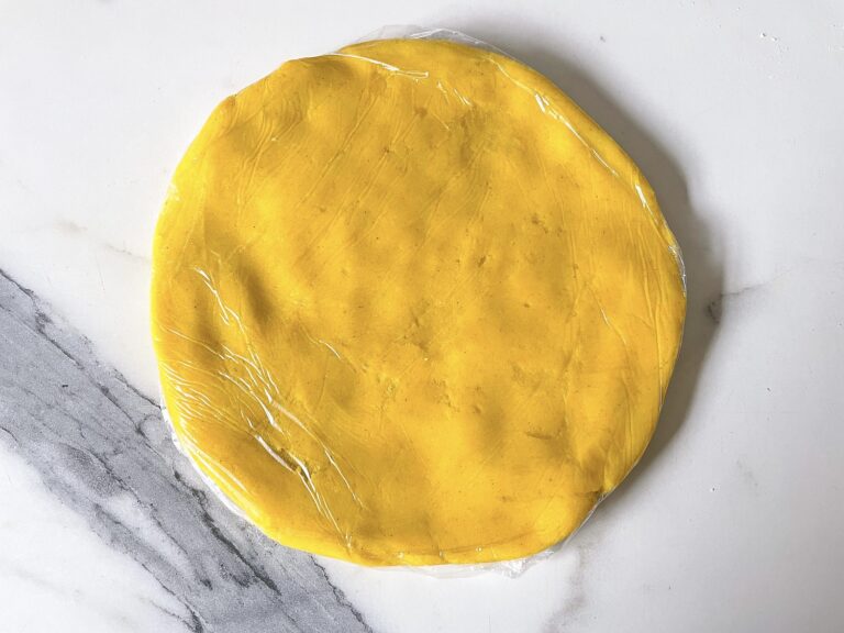 Yellow dough flattened into a disc for chilling