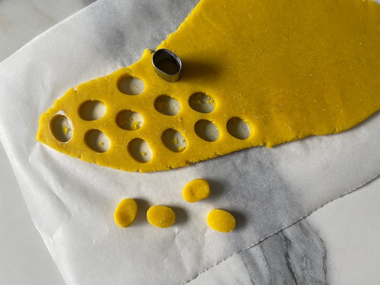 Cutting yellow dough with a small round cutter