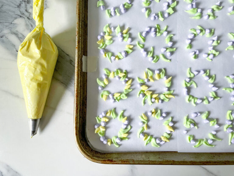 Piping yellow meringue onto a tray for floral wreath meringue cookies recipe